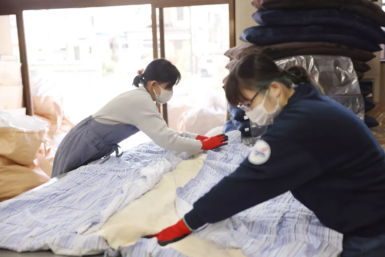 布団を広げて生地と中綿を丁寧に分けている様子